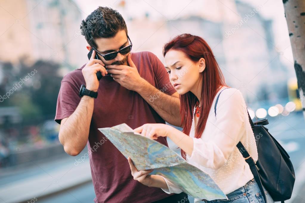 Couple of travelers using map in city