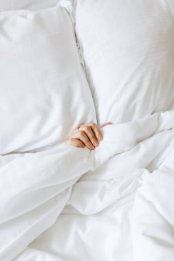Kırpılmış kadın eli beyaz yatakta