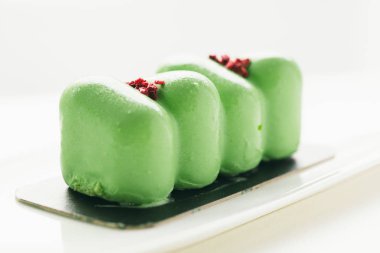 Gri arkaplandaki mini yeşil kremalı pastayı kapat.