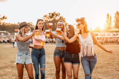 Güzel genç kadınlar bira içip müzik ve sanat festivalinde eğleniyorlar.