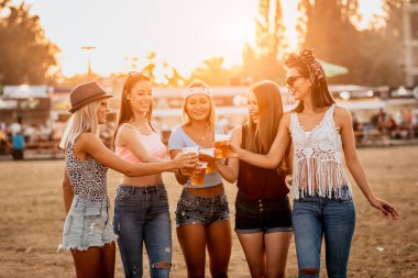 Güzel görünümlü genç kadınlar bira içiyor ve festivalde hafta sonları müzik başlıyor. 