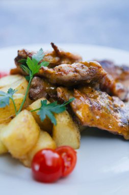Fırında patatesle lezzetli bir yemek ve beyaz tabakta biftek.