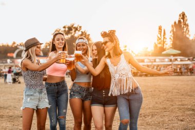 Güzel genç kadınlar bira içip müzik ve sanat festivalinde eğleniyorlar.