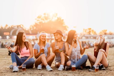 Güzel görünümlü genç kadınlar bira içiyor ve festivalde hafta sonları müzik başlıyor. 