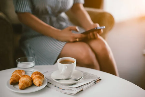 Γυναίκα Κρατώντας Smartphone Και Κάθεται Στην Καρέκλα Πρωινό Φλιτζάνι Καφέ — Φωτογραφία Αρχείου