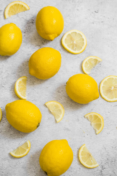 ripe, juice and fresh halved and slices of lemons on gray background 