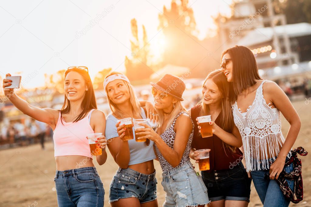 happy and funny girlfriends enjoying beginning of holidays on festival