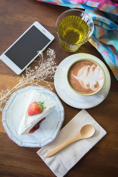 coffee cup and delicious cake strawberry and relax time moblie on table in coffee shop
