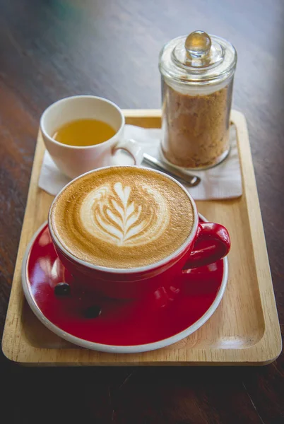 Aroma café vermelho copo latte arte e bolo saboroso na mesa de madeira no café — Fotografia de Stock