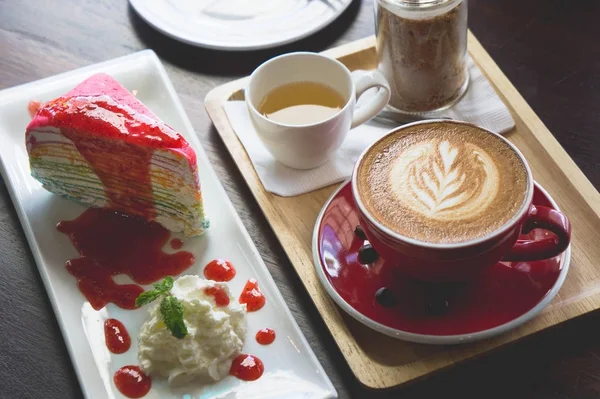 red coffee cup latte art and cake on wood table in coffee shop