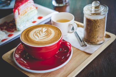 latte sanat ve lezzetli kek kafede vintage koyu tonu ve kopya alanı olan ahşap masa üzerine fincan kahve aroması kırmızı