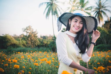 güzel kadın Asya tarzı sarı çiçek bahçesi ve seyir gülümseme mutlu zaman gününde