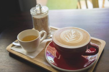 latte sanat ve lezzetli kek kafede vintage koyu tonu ve kopya alanı olan ahşap masa üzerine fincan kahve aroması kırmızı