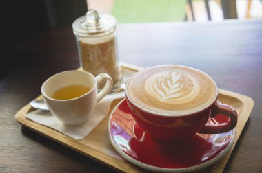 latte sanat ve lezzetli kek kafede vintage koyu tonu ve kopya alanı olan ahşap masa üzerine fincan kahve aroması kırmızı