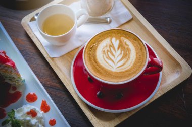 latte sanat ve lezzetli kek kafede vintage koyu tonu ve kopya alanı olan ahşap masa üzerine fincan kahve aroması kırmızı