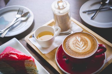 latte sanat ve lezzetli kek kafede vintage koyu tonu ve kopya alanı olan ahşap masa üzerine fincan kahve aroması kırmızı