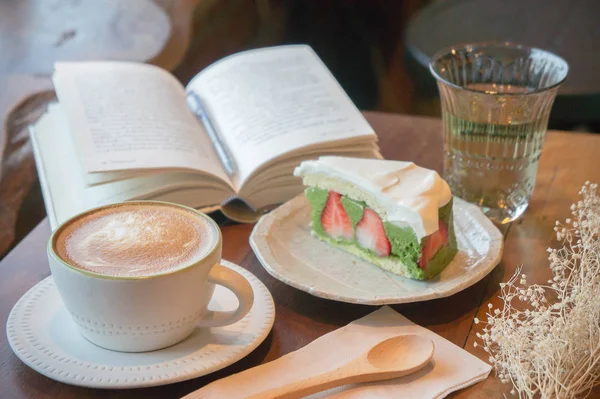 Pohled shora coffee cup a zelený čaj dort, chytrý telefon, kniha na stůl v kavárně uvolnit čas — Stock fotografie
