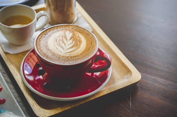 Aroma café vermelho copo latte arte e bolo saboroso na mesa de madeira no café com tom escuro vintage e espaço de cópia — Fotografia de Stock