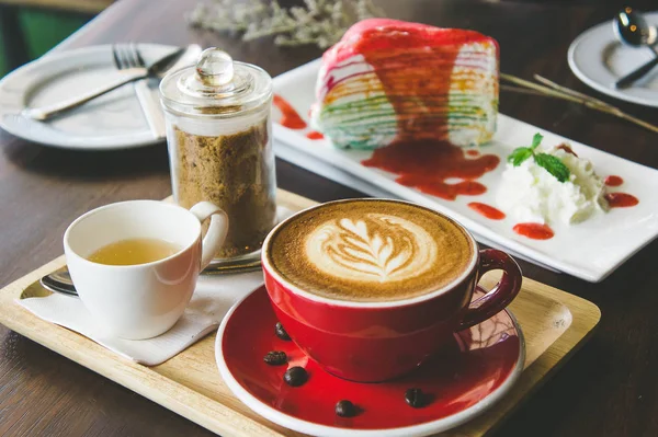 aroma coffee red cup latte art and tasty cake on wood table in coffee shop with vintage dark tone and copy space