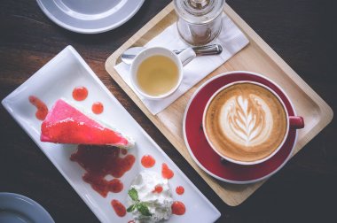 latte sanat ve lezzetli kek kafede vintage koyu tonu ve kopya alanı olan ahşap masa üzerine fincan kahve aroması kırmızı