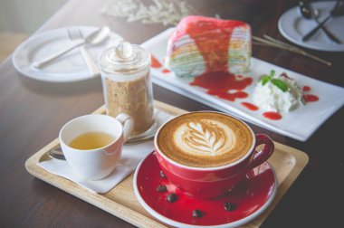 latte sanat ve lezzetli kek kafede vintage koyu tonu ve kopya alanı olan ahşap masa üzerine fincan kahve aroması kırmızı