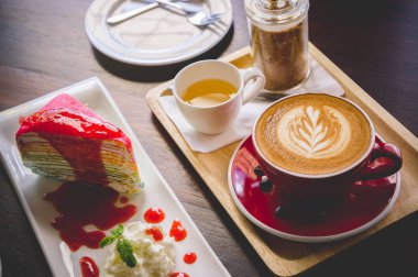 latte sanat ve lezzetli kek kafede vintage koyu tonu ve kopya alanı olan ahşap masa üzerine fincan kahve aroması kırmızı