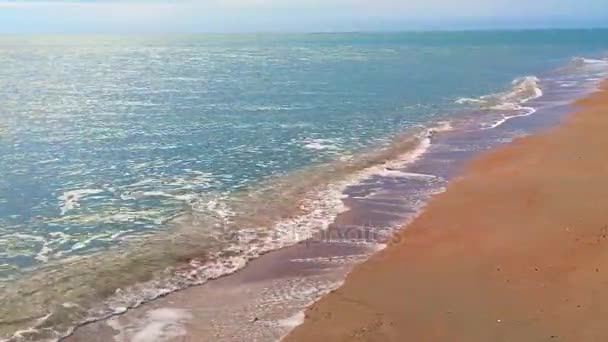 曇り空は大きく、重い雲の下で人けのないビーチ、青い水と黄色の砂の海または海の波 — ストック動画