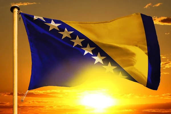 Bandera de Bosnia y Herzegovina tejiendo en la hermosa puesta de sol naranja con fondo de nubes — Foto de Stock