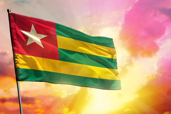 Fluttering Togo bandeira no belo pôr do sol colorido ou fundo do nascer do sol. Conceito de sucesso . — Fotografia de Stock