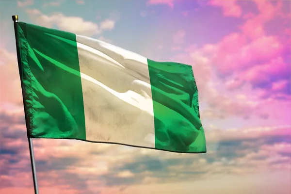 カラフルな曇り空の背景にナイジェリアの旗をなびかせます。繁栄の概念. — ストック写真