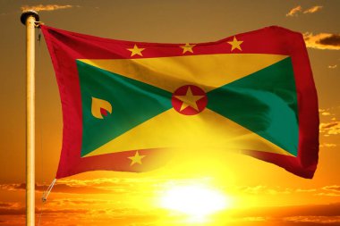 Grenada bayrağı bulutların ardında güzel turuncu günbatımında zikzak çiziyor.