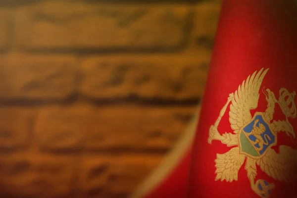 Flaga Czarnogóry na cześć dnia weteranów lub dnia pamięci. Chwała czarnogórskim bohaterom koncepcji wojennej na pomarańczowym, zamazanym tle z cegły. — Zdjęcie stockowe