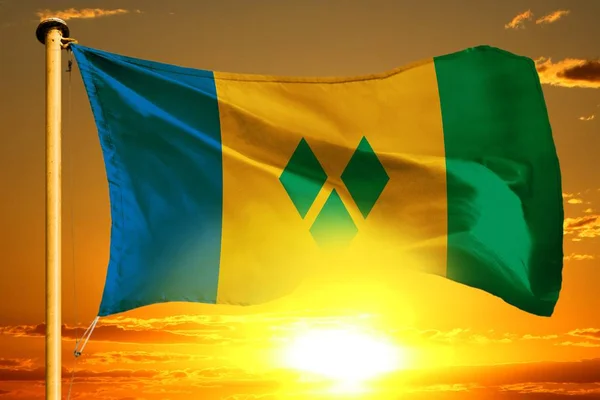Saint Vincent und die Grenadinen Flagge weben auf dem schönen orangen Sonnenuntergang mit Wolken Hintergrund — Stockfoto