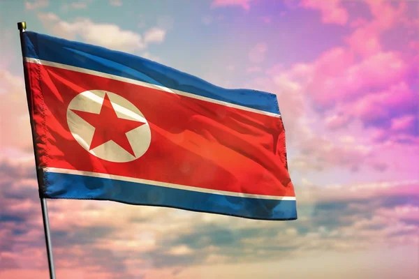 Fluttering Λαϊκή Δημοκρατία της Κορέας (Βόρεια Κορέα) σημαία σε πολύχρωμο θολό φόντο του ουρανού. Έννοια της ευημερίας. — Φωτογραφία Αρχείου