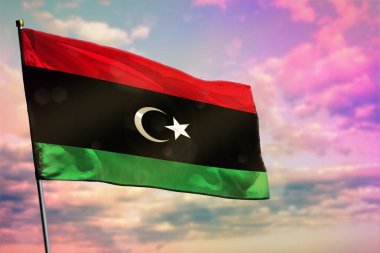 Renkli bulutlu arka planda dalgalanan Libya bayrağı. Libya refah konsepti.