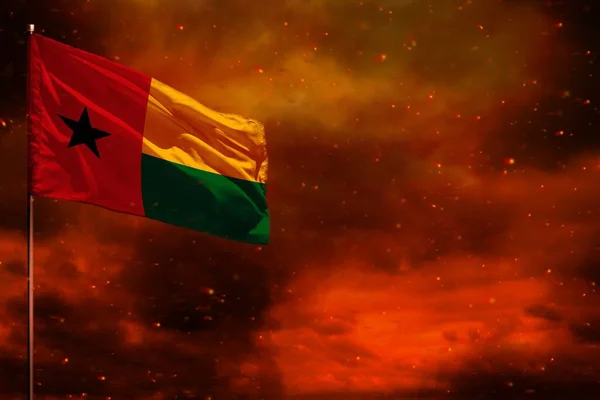 Fluttering Guinea-Bissau flag mockup with blank space for your data on crimson red sky with smoke pillars background. Guinea-Bissau problems concept.