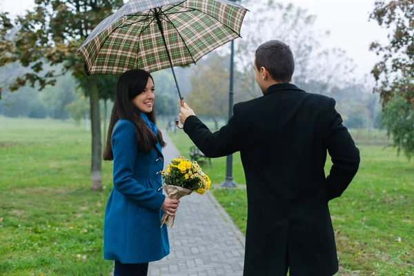 Jovem segurando um guarda-chuva sobre sua namorada — Fotografia de Stock