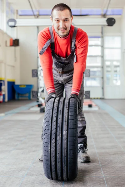 Homem empurrando um pneu preto — Fotografia de Stock
