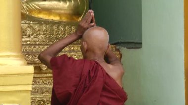 Budist keşiş turuncu elbise ile sıktı elleriyle tapınakta dua