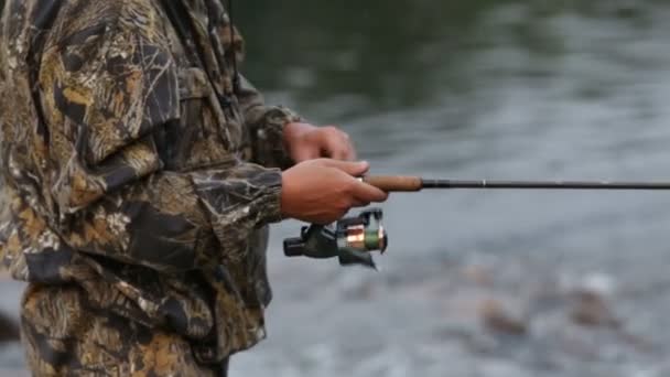 Un hombre con ropa de camuflaje está pescando para hacer girar — Vídeo de stock