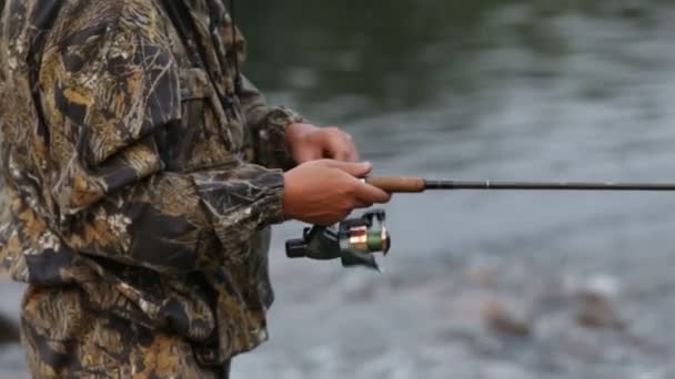 Un uomo in abiti mimetici è la pesca per la filatura — Video Stock