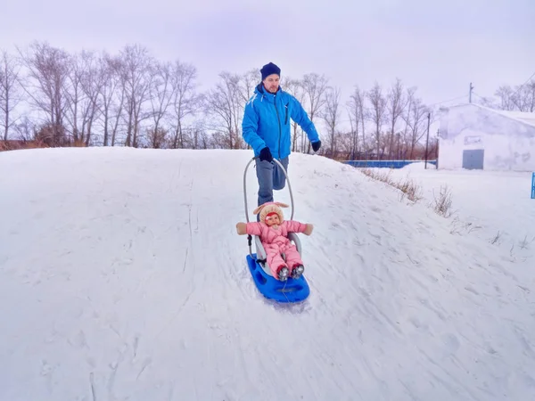 Vader met kind lopen de slee in de winter op sneeuw. — Stockfoto