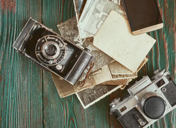 Three generations of a photo cameras and old photos on memory. Ancient authentic wooden background — Stock Photo, Image