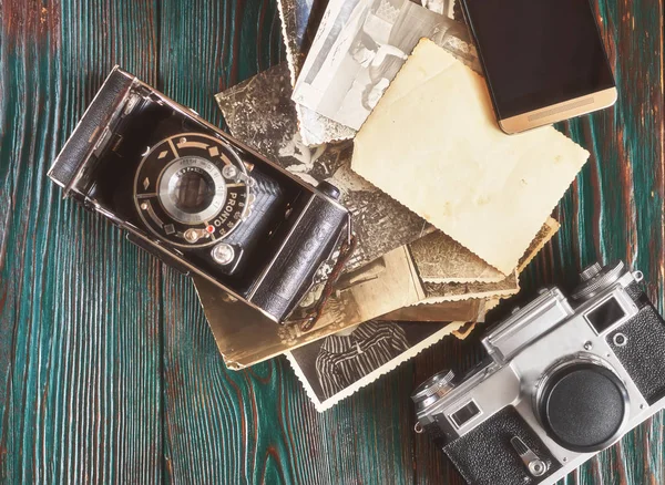 Three generations of a photo cameras and old photos on memory. Ancient authentic wooden background — Stock Photo, Image