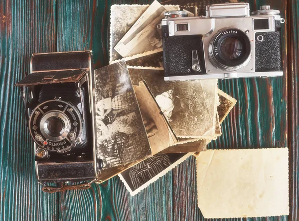 Three generations of a photo cameras and old photos on memory. Ancient authentic wooden background — Stock Photo, Image