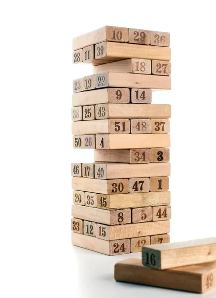 Blokken van spel jenga geïsoleerd op een witte achtergrond. Verticale toren geheel en in het spel. Houten blokken in de stapel met cijfers cijfers op lichaam. — Stockfoto