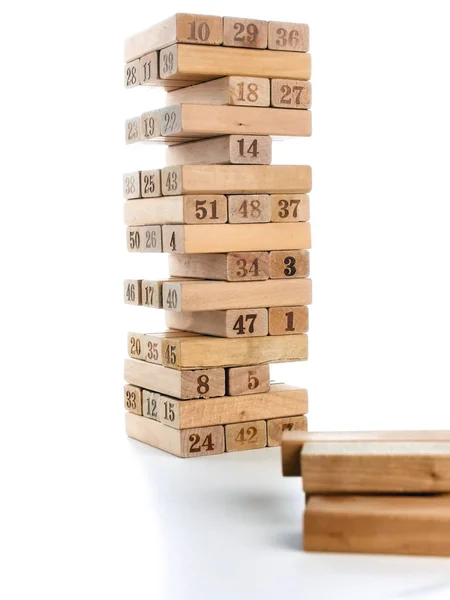 Blokken van spel jenga geïsoleerd op een witte achtergrond. Verticale toren geheel en in het spel. Houten blokken in de stapel met cijfers cijfers op lichaam. — Stockfoto