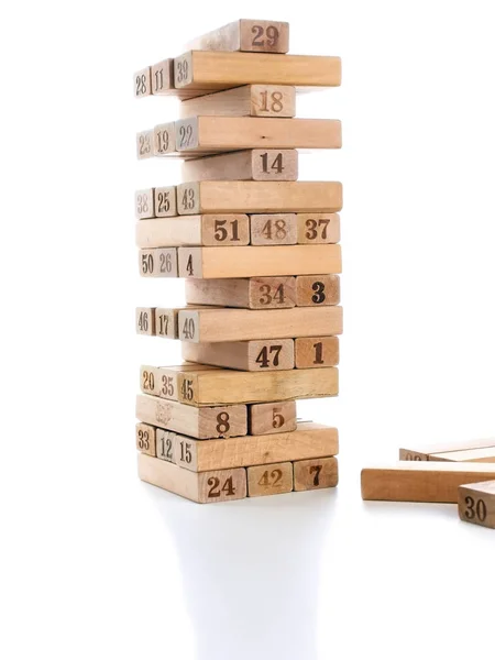 Blokken van spel jenga geïsoleerd op een witte achtergrond. Verticale toren geheel en in het spel. Houten blokken in de stapel met cijfers cijfers op lichaam. — Stockfoto