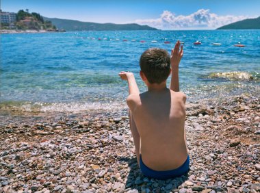 Su deniz taş atan genç çocuk. Çöl beach Hertseg Novi. Kotor Körfezi, Karadağ