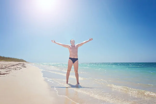 Happy man on beach. Rejoices to a victory success, hands up. Cuba, playa Ankon Trinidad Caribbean Sea. Stock Photo
